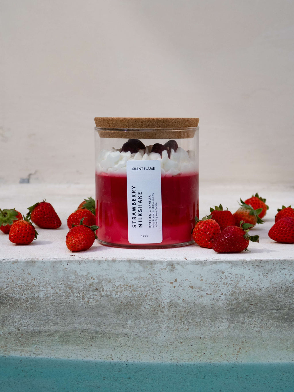 Strawberry milkshake candle with strawberries on a textured surface